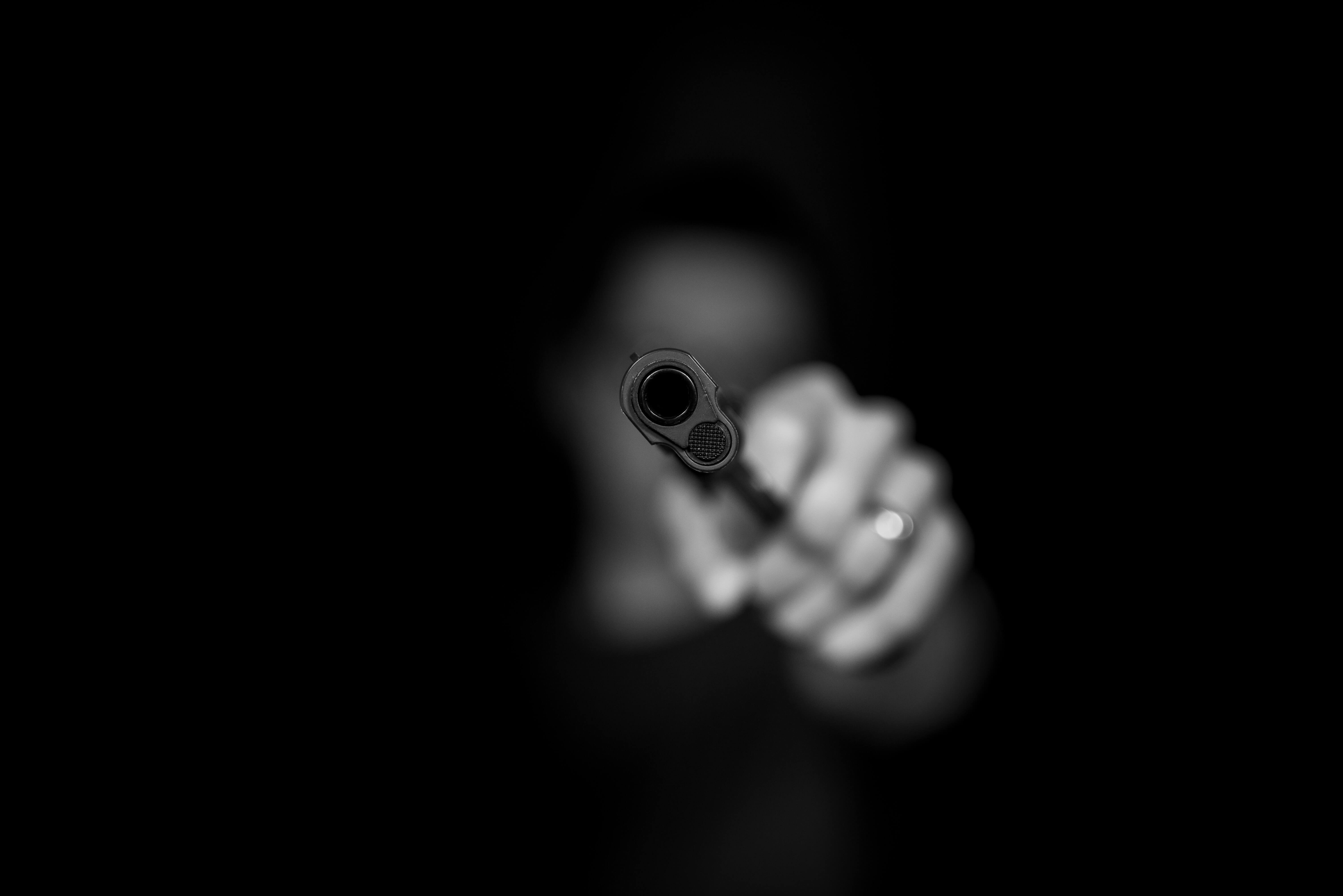 een donkere foto van een onherkenbare man die zijn pistool richt